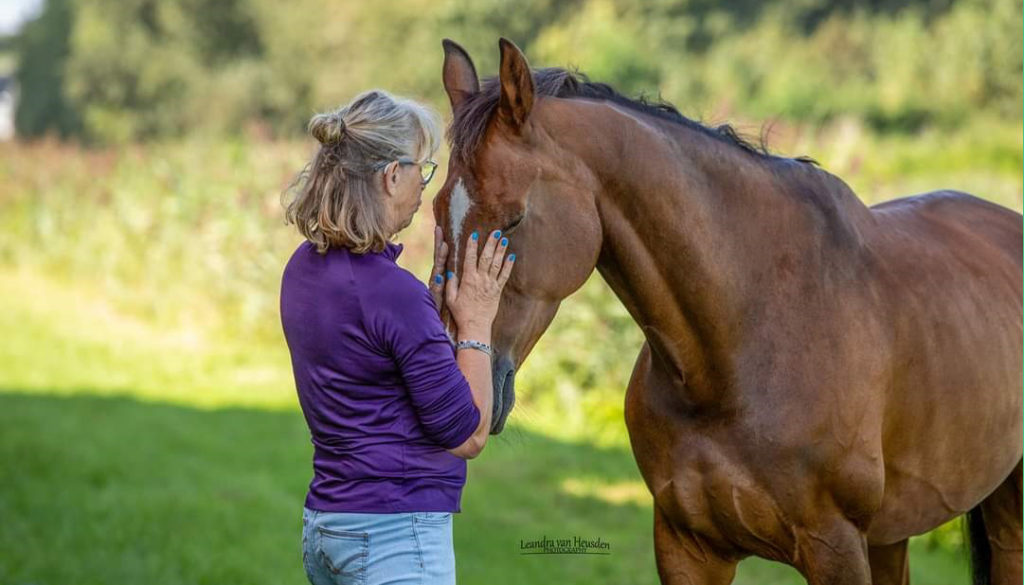 Begeleidster Ans van connective horses aait een paard.