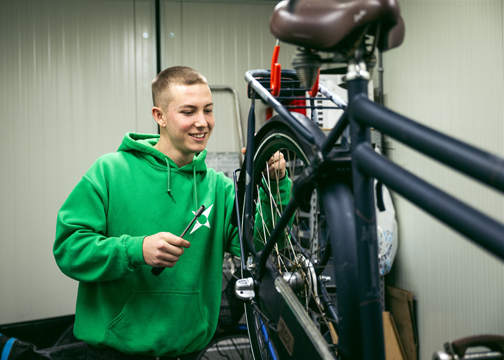 Jongen die aan een fiets sleutelt.